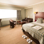 Angled view of Double bed, desk, HDTV, slippers and dressing gowns in a Privilege Room at Mercure Hotels