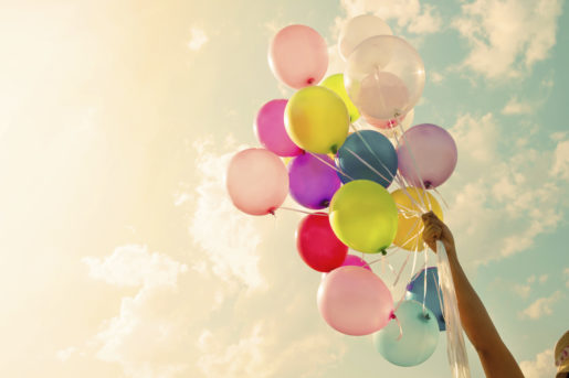 Girl hand holding colorful balloons. happy birthday party. vintage filter effect