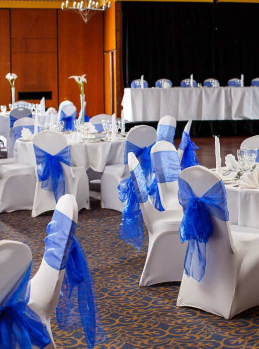 The City Suite at Mercure Norwich Hotel, set up for a wedding breakfast, white linen with blue sashes