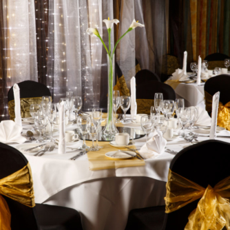 The City Suite at Mercure Norwich Hotel, set up for a wedding breakfast, black linen with yellow sashes