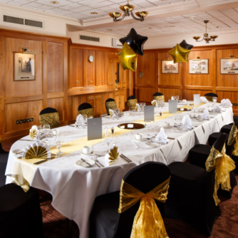 The Club Room at Mercure Norwich Hotel, set up for a wedding breakfast, black and gold theme, star balloons, wood panelling on walls