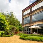 Exterior shot of the gardens at Mercure Norwich Hotel, gravel path, lawn, benches, patio area