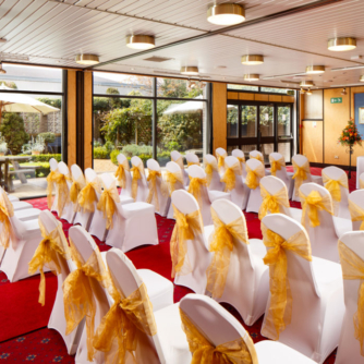 The Presidential Suite at Mercure Norwich Hotel set up for a wedding ceremony, red carpet aisle, white and yellow theme, garden views from window