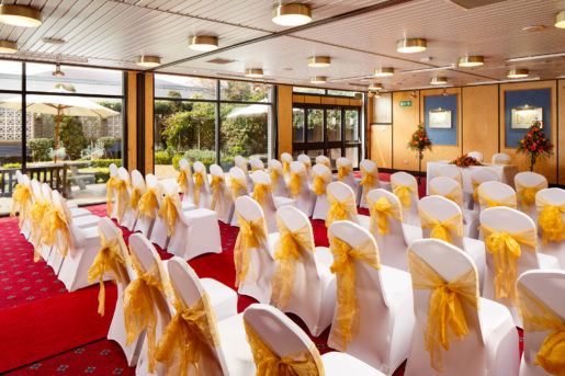 The Presidential Suite at Mercure Norwich Hotel set up for a wedding ceremony, red carpet aisle, white and yellow theme, garden views from window
